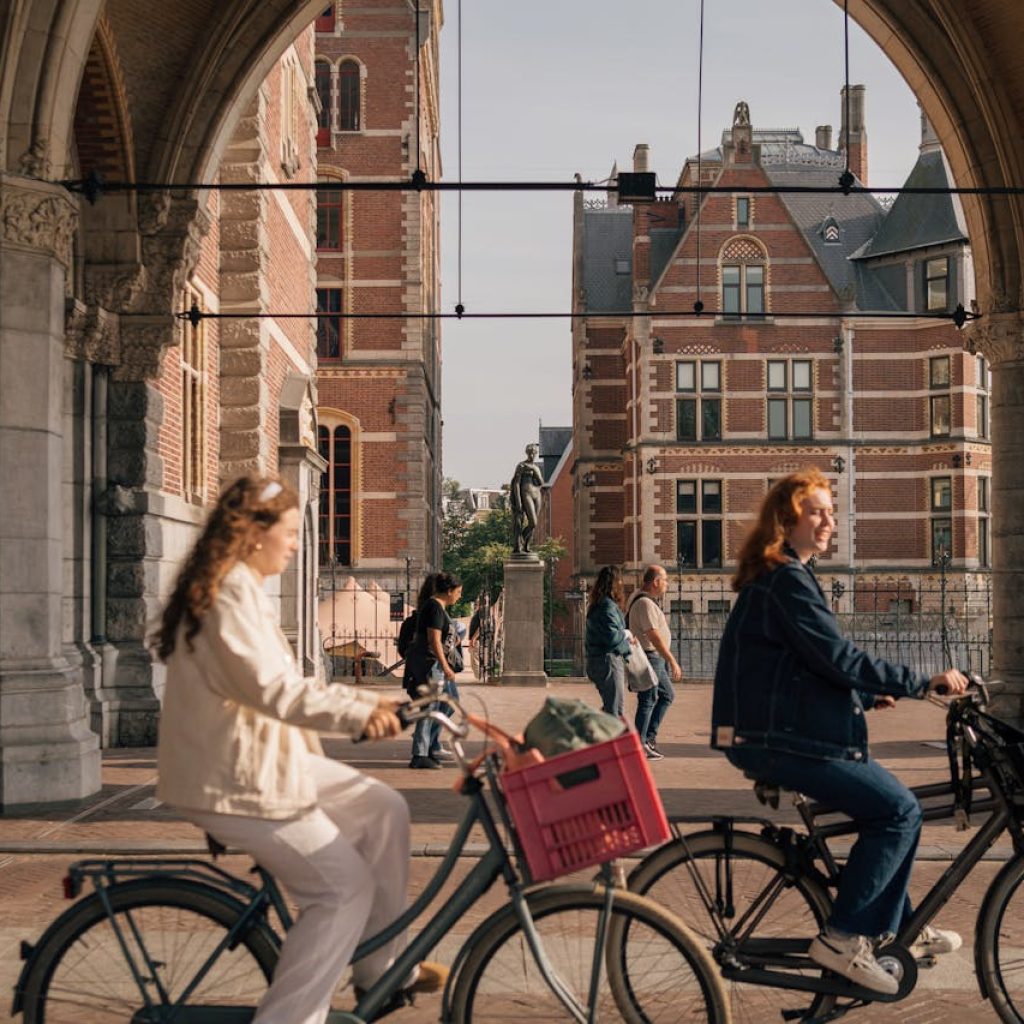 Cyclists passing by the historic Rijksmuseum in Amsterdam, the city inspiring ASML SEO Company's innovative strategies