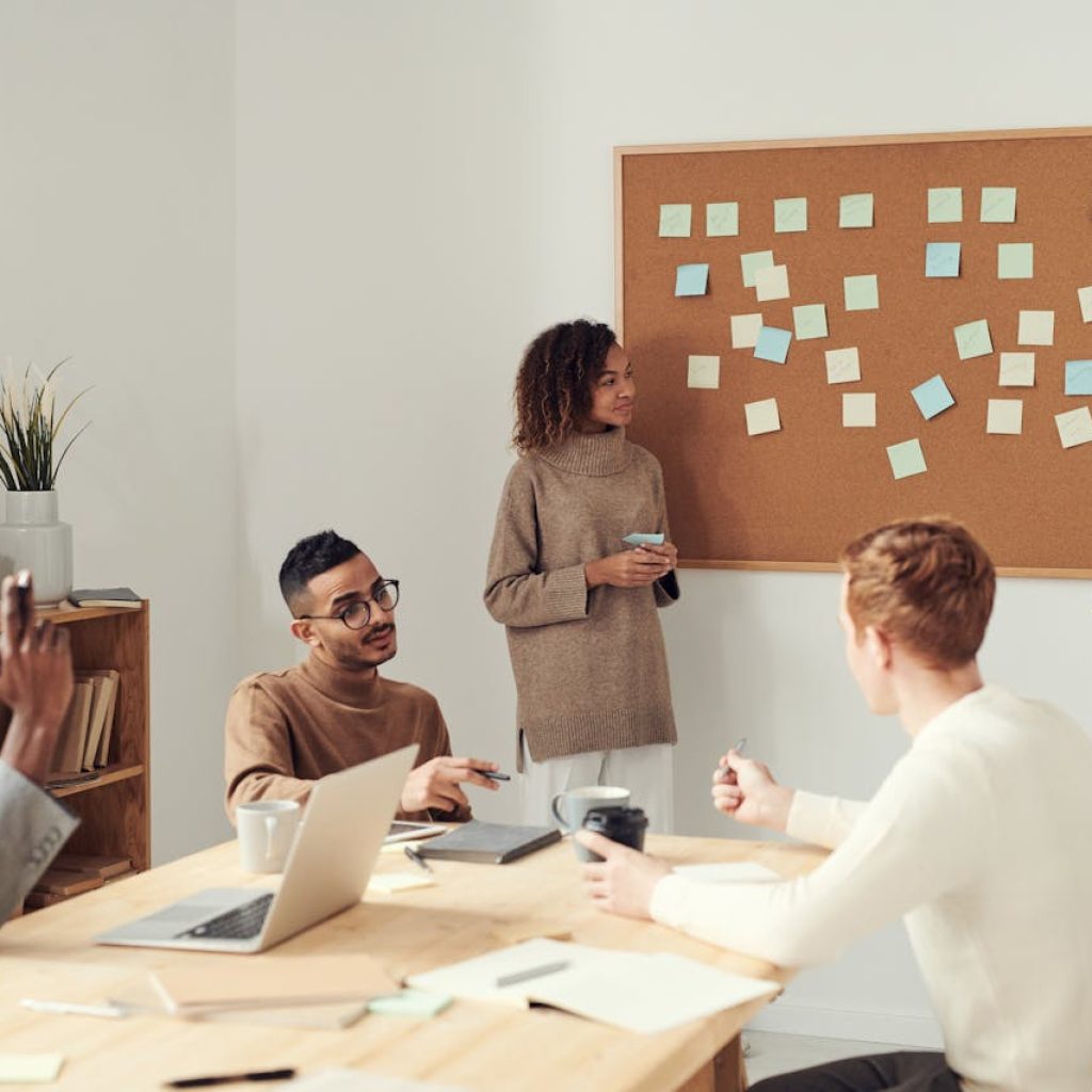 A SEO dynamic team at a company strategizes around a bulletin board in a modern office setting