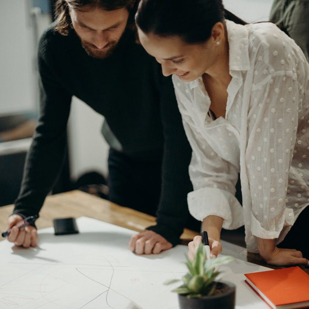 Two SEO specialists analyzing strategy plans on paper in a workshop setting.