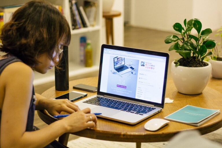 A focused individual studies for the Google Search Engine Optimization Certification online, surrounded by tech devices and a plant, symbolizing growth in knowledge.